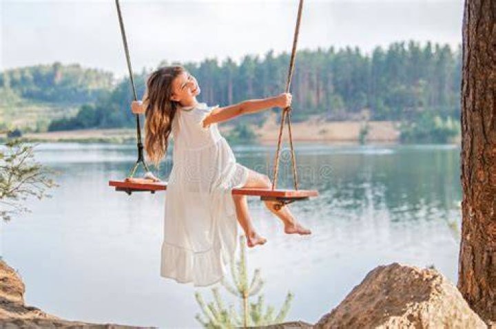 Girl swinging by lake Stock Photo Alamy