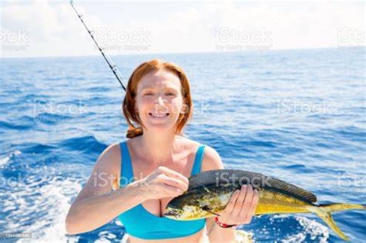 Woman fishing Dorado Mahimahi fish happy with trolling catch on boat